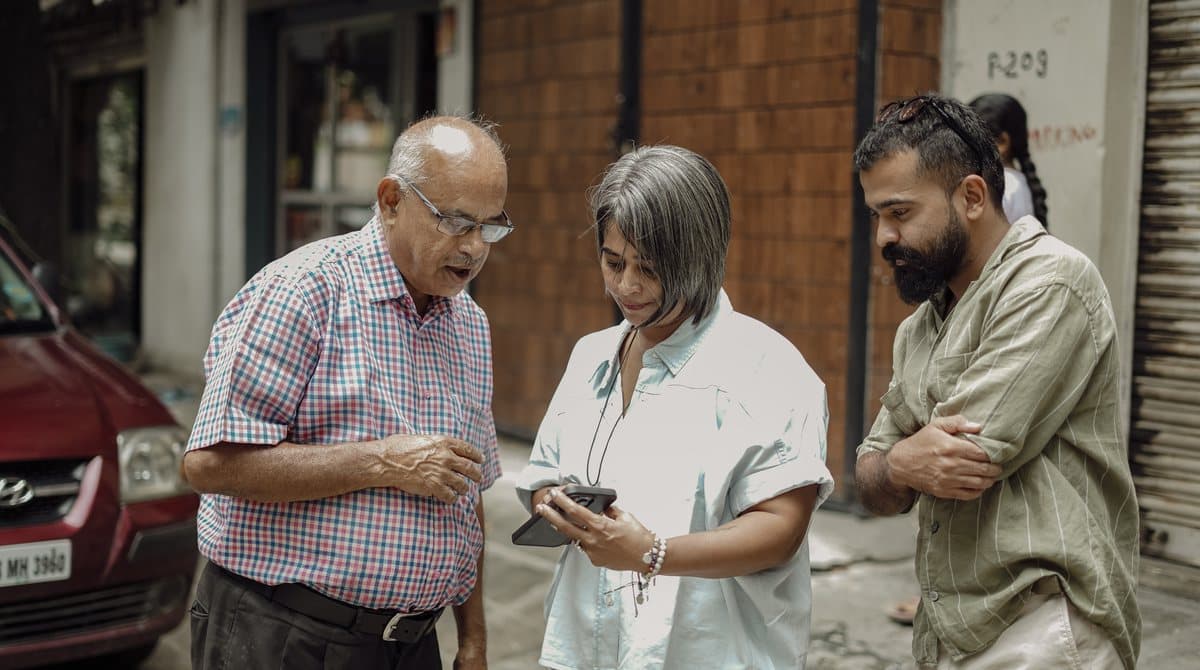 A Concierge going over something on a phone with an elder out on the street